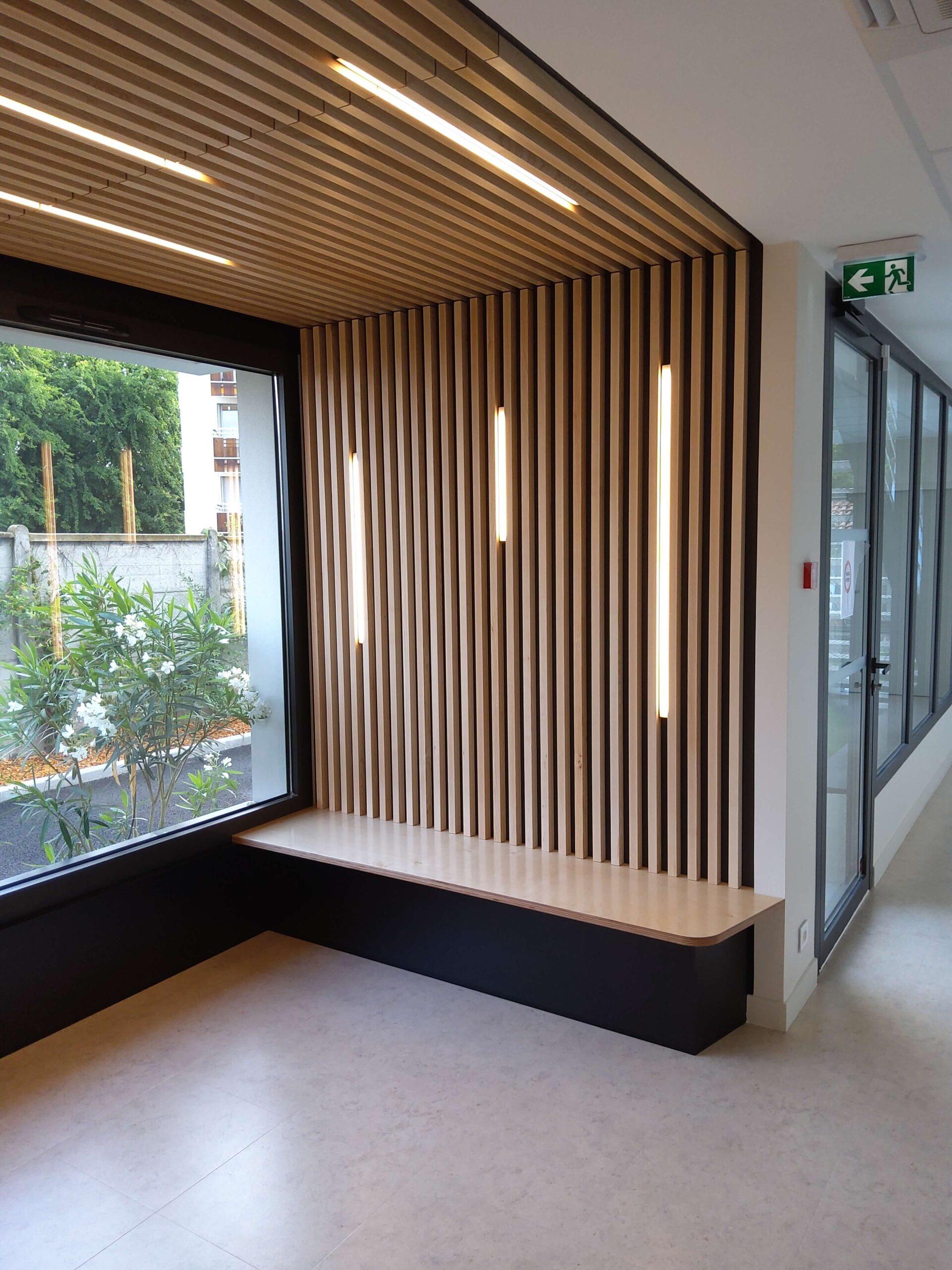 espace-attente Espaces d’attente avec des bancs en contre-plaqué bouleau vernis, soubassement en stratifié noir, panneaux de dossier et de plafonds en tasseaux frêne vernis naturel avec fixation invisible sur panneaux mélaminé finition touch et intégration de bandeaux Led en coordination avec le lot électricité.
